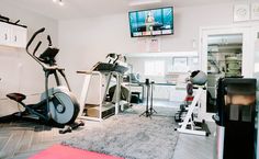 an exercise room with treadmills, television and other equipment on the wall in front of it