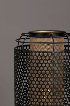 a black and gold vase with holes on it's sides, sitting against a gray background