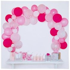 a table topped with lots of pink and white balloons