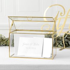 a glass box with two cards inside it on top of a table next to flowers