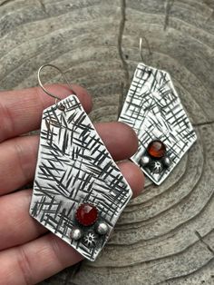 These large earrings are unique and eye catching.  They are hand forged from 925 Sterling silver and features beautiful red carnelian gemstones.  The metal has been textured with a hatched pattern and the gemstone is accentuated with hand crafted Sterling silver elements. Ear wires are 20g Sterling silver. These earrings are fairly hefty but not too large that they would be uncomfortable for most people.  Carnelian is considered a birthstone for those born in July but of course it's timeless for everyone! Measures approx: 78mm L X 4cm W at widest point These earrings are ready to ship and will arrive attractively packaged and ready for gifting or keeps.  Please read shop policies before ordering. Metalsmith Jewelry, Born In July, Red Carnelian, Metalsmithing Jewelry, July Birthstone, Large Earrings, Geometric Earrings, How To Make Earrings, Hand Forged