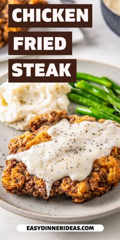 chicken fried steak on a plate with mashed potatoes and asparagus in the background