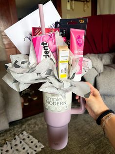 a person holding up a pink cup with some items in it