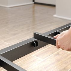 a person is holding the handle on a metal bed frame in a room with wood floors