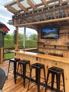 an outdoor bar with four stools and a television