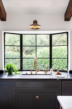 a kitchen with black cabinets and an open window over the sink is seen in this image