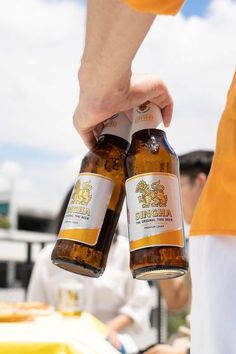 two bottles of beer being held by people