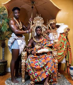 three men dressed in african clothing and holding an umbrella