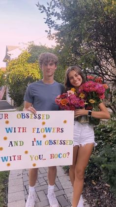 a man and woman standing next to each other holding a sign that says your dressed with flowers and i'm obsesed with you?