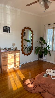 a bedroom with wooden floors and a mirror on the wall above it, next to a bed