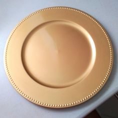 an empty gold plate sitting on top of a white countertop next to a knife and fork