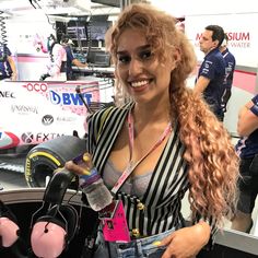 a woman with long hair is standing in front of a car at an auto show