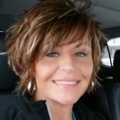 a woman sitting in the back seat of a car with short hair and blue eyes