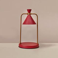 a red table lamp sitting on top of a wooden stand