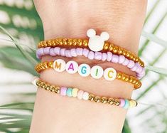 three different bracelets with mickey mouse charms on each one and the word magic written in white letters