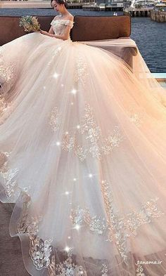 a woman is sitting on a bench wearing a wedding dress with flowers in the skirt