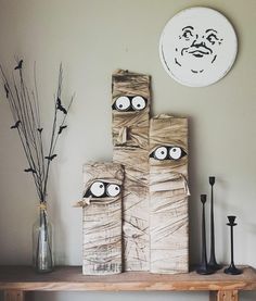 a wooden table topped with boxes and vases next to a wall mounted clock on the wall