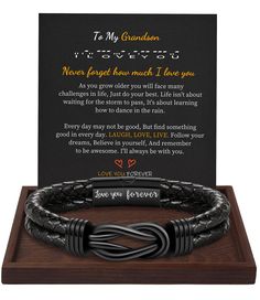 a black leather bracelet with an engraved message on it and a wooden plaque in the background