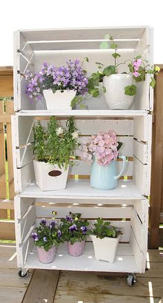 a white shelf filled with potted plants on top of a wooden floor next to a fence