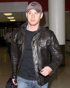 a man wearing a hat and carrying a suitcase in his hand at an air port