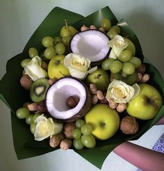 a bouquet of fruit and flowers is arranged in the shape of an apple, kiwi, grapes, almonds