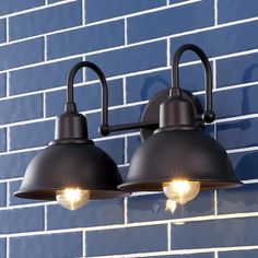 two lights are attached to the side of a blue brick wall