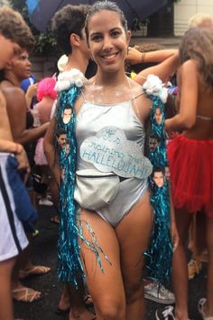 a woman in a silver bodysuit and blue fringes standing next to other people