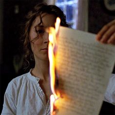 a woman reading a book while holding a lit candle