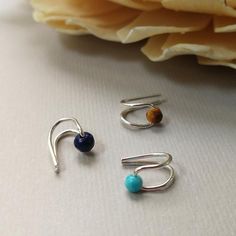 three pieces of silver jewelry sitting on top of a table next to a flower bouquet