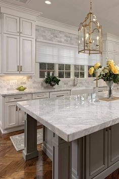 a large kitchen with marble counter tops and white cabinets, along with an island in the middle