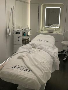 a hospital room with a bed, sink and mirror