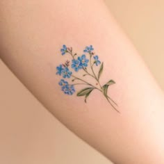 a small blue flower tattoo on the arm