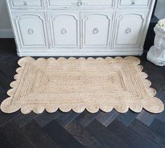 a rug on the floor in front of a dresser and white cabinet with drawers behind it