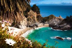 the beach is surrounded by trees and blue water