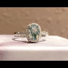 a close up of a ring with a stone in the middle and diamonds around it