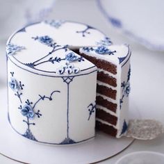 a white cake with blue flowers and a slice missing from it on a platter