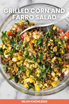 grilled corn and faro salad in a glass bowl with a spoon on the side