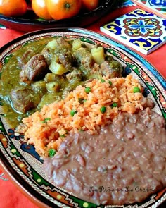 a plate with rice, beans and meat on it next to oranges in a bowl