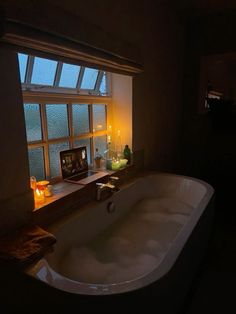 a bathtub sitting in front of a window next to a candle and some candles