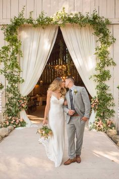 a bride and groom kissing in front of an open barn door at their wedding reception