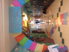 a hallway decorated in rainbow colors with people walking down the hall and lockers on either side