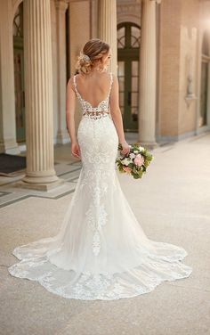 a woman in a wedding dress is standing on the sidewalk with her back to the camera