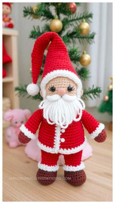 a crocheted santa clause doll next to a christmas tree