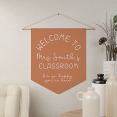 a welcome sign hangs on the wall above a table with vases and other items