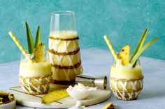 three glasses filled with pineapple milkshakes on top of a table