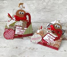 two small christmas gift bags on a white wooden table with red and green tags attached to them