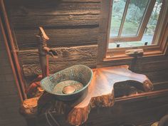 a bowl shaped sink sitting on top of a wooden table in front of a window