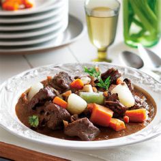 a white plate topped with meat and vegetables on top of a table next to plates