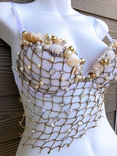 a white mannequin with pearls and seashells on it's back