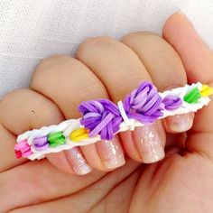 a hand holding a tiny bow no loom nail art decoration on it's fingers